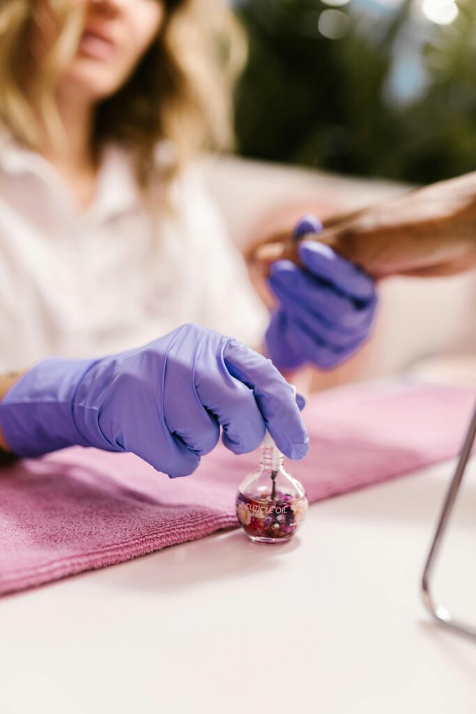 Close-up of a manicure process in a salon with purple gloves and polish.